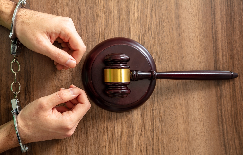 Hands holding a gavel and sound block on a wooden desk